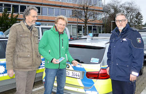 Der erste Aufkleber ist befestigt: Rob Maris und Jens Veith starteten mit Polizeihauptkommissar Guido Machunske die Aktion "Abstand halten". Foto: Polizei