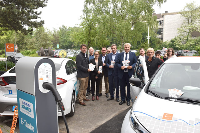 Cambio-Geschäftsführerin Gisela Warmke (vorne, r.) und Landrat Wolfgang Spelthahn stellten das neue Car-Sharing-Angebot am Kreishaus Düren vor. Zwei Mietwagen stehen dort bereit, darunter einer mit Elektromotor. Foto: Kreis Düren