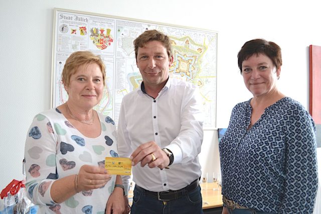 Bürgermeister Axel Fuchs (Mitte) überreichte gemeinsam mit Anne Gatzen vom Amt für Stadtmarketing (r.) die 100. Ehrenamtskarte an Brigitte Barton-Wöllm (l.). Foto: Stadt Jülich/Stein