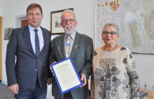 Stolz auf 40 Jahre Mitgliedschaft und Engagement in der Verkehrswacht Jülich: Hartmut Dreßen kam in Begleitung seiner Frau Karin ins Rathaus, wo Bürgermeister Axel Fuchs ihm zum Erhalt der Ehrenurkunde gratulierte. Foto: Stadt Jülich/Gisa Stein