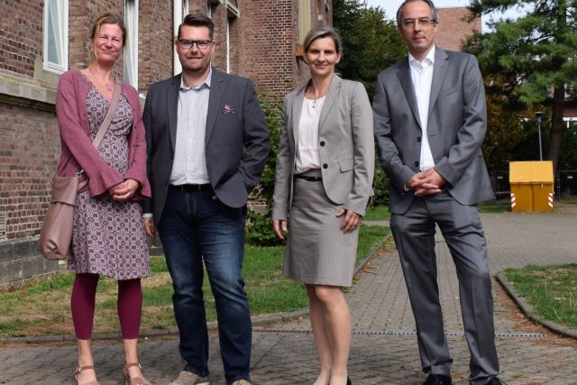 Gemeindesozialarbeiterin Sylvia Karger, Stefan Helm vom Sozialamt der Stadt Linnich, Bürgermeisterin Marion Schunck-Zenker und Caritas-Vorstand Dirk Hucko auf dem Hof der Unterkunft Alte Polizeischule. Foto: Erik Lehwald / Caritasverband Düren-Jülich e.V.